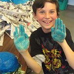A smiling child with blue paint on both hands