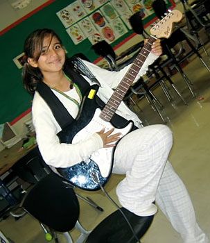 A young girl playing an electric guitar